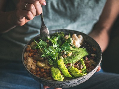 Hands holding a salad bowl full of healthy ingredients