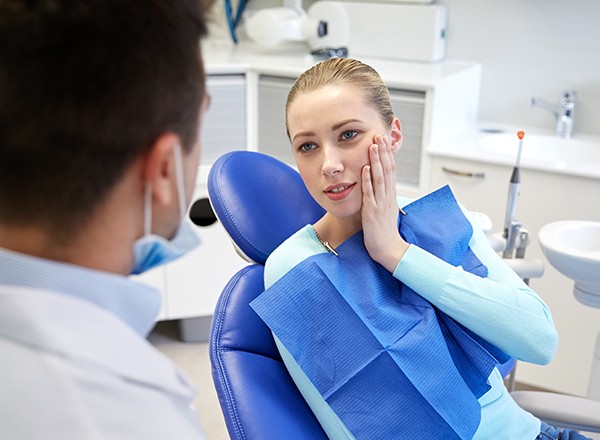 Woman in dental chair holding cheek