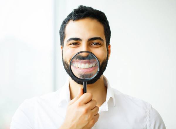 man showing off his smile with a magnifying glass 