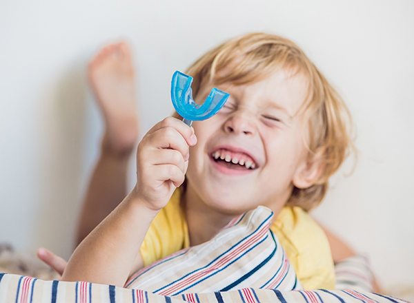 Smiling child holding mouthguard