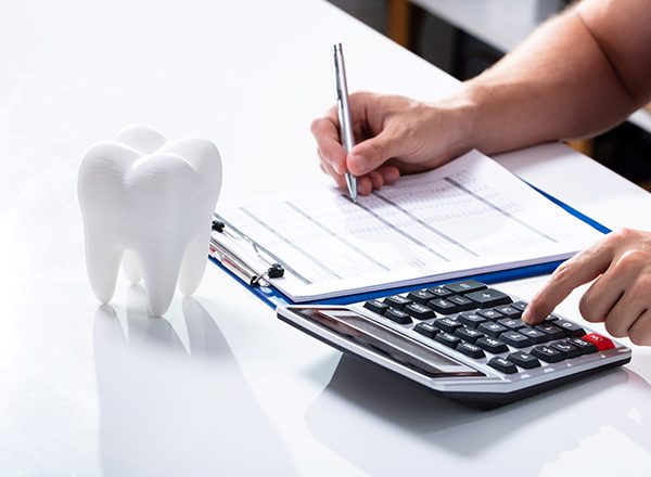 Using a calculator to figure out cost; model tooth on table