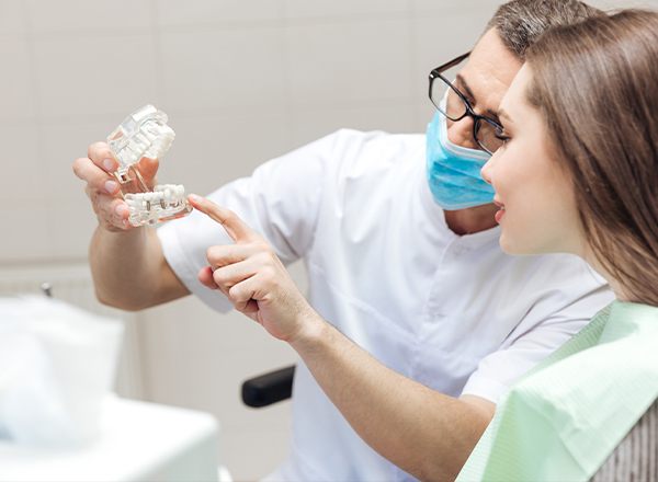 Dentist showing patient dental implant smile model