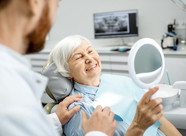 Older woman in dental chair looking at new smile
