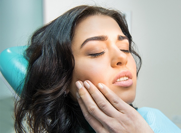 Woman in dental chair holding jaw