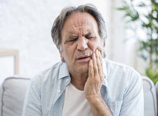 Older man holding cheek in pain