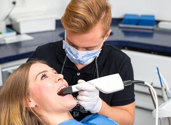 A dentist taking digital impressions of a female patient’s mouth