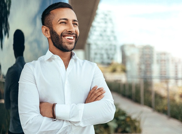 A younger man standing outside and smiling