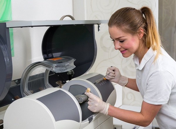 A dental assistant placing a piece of ceramic into a milling unit