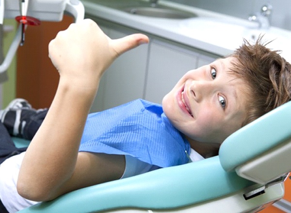 A child sitting in a dental chair smiling.