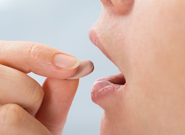 Closeup of patient taking oral sedative pill