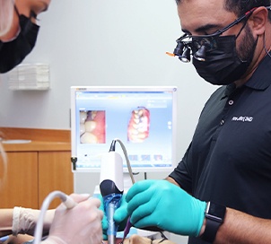 Dentist and team member helping dental patient