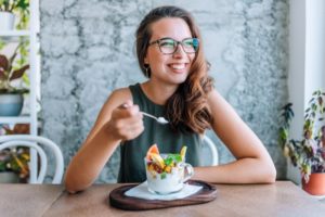 Woman eating a healthy snack while looking towards the window