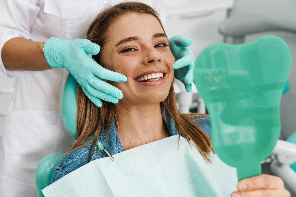 Woman smiling while holding mirror in treatment chair